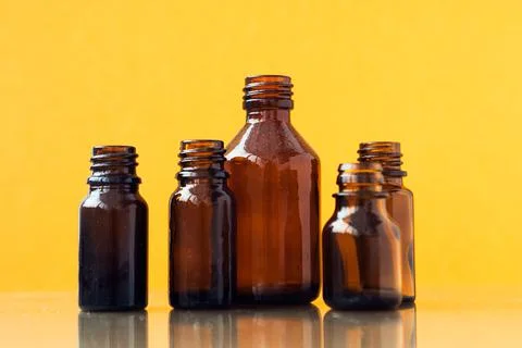 Dark brown phials on yellow background. Small empty bottles Stock Photos