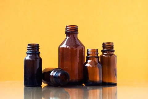 Dark brown phials on yellow background. Small empty bottles Stock Photos