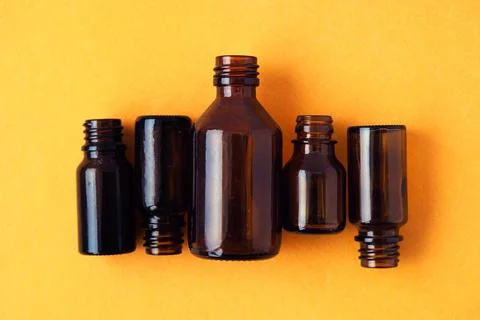 Dark brown phials on yellow background. Small empty bottles Stock Photos