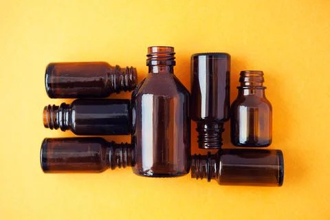 Dark brown phials on yellow background. Small empty bottles Stock Photos