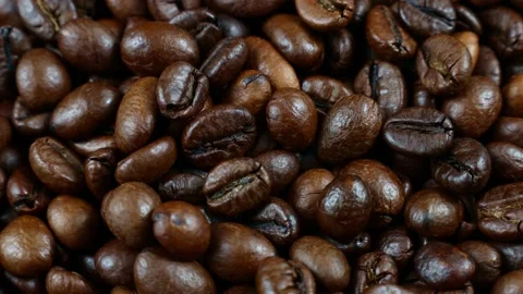 Dark brown roasted coffee beans falling down on rotating background Video stock 232288710