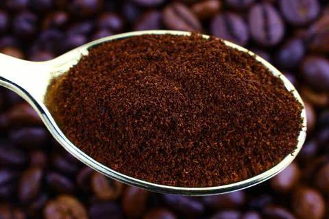 Dark brown roasted coffee beans and ground coffee powder in spoon top view Stock Photos
