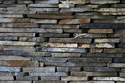 Dark brown rough stone wall. Brick wall stack background. Stock Photos