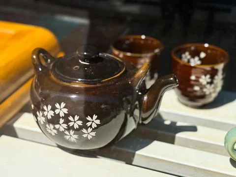 Dark brown teapot with floral pattern. Ceramic teaware set decorated with white Stock Photos
