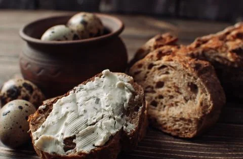 Dark buckwheat bread is spread with cottage cheese with herbs in a cut Stock Photos