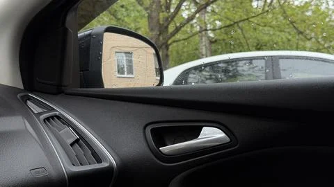 Dark car interior featuring a metallic door handle and the side rearview mirror Stock Photos