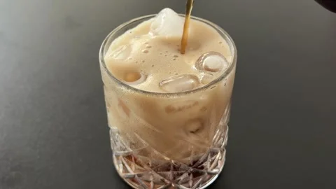 Dark Carbonated Soft Drink Pouring Over Ice Cubes in Clear Glass on Gray Stock Footage 345172274