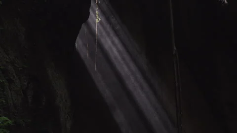 Dark Cave, illuminated by rays of light penetrating through the stone ceiling Stockbeeldmateriaal 277152342