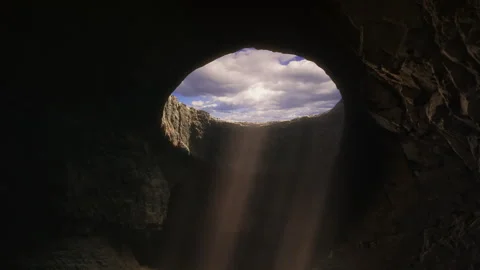 Dark Cave Opening With Sunbeams Framing Blue Cloudy Sky 库存影片 342249265