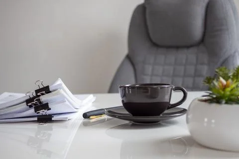Dark ceramic cup sits on a sleek white desk Stock Photos