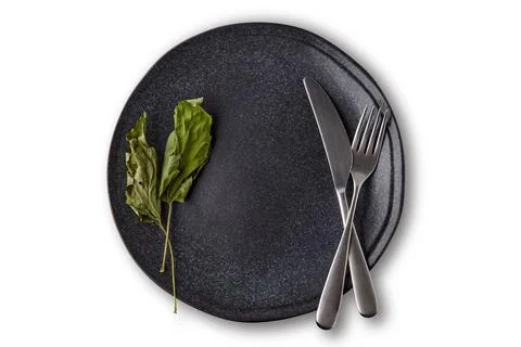 Dark ceramic plate dish decorated with dried currant leaves with cutlery Foto stock