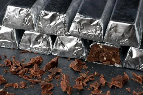 Dark chocolate broken bars in stack and grated chocolate on a dark table Stock Photos