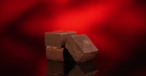 Dark chocolate cubes rotating on red background. Close up view filmed with RED Stock Footage 155075736