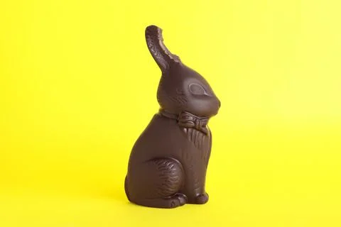 Dark chocolate Easter bunny with bite mark on yellow background Foto stock