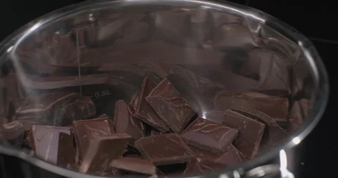 Dark chocolate falls into a pan. Preparation of melted chocolate for premium Stock Footage 252744486