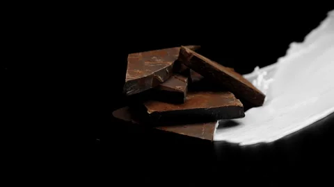 Dark chocolate stack covered by splashing white milk and cocoa drink, slow mo Stock Footage 141985912