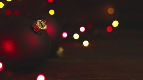 Dark Christmas baubles on rustic table against defocused colourful lights. Stock Footage 285962225