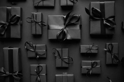 Dark Christmas theme. Square boxed gifts wrapped in black paper and ribbon Stockfoto's