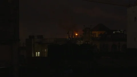 Dark city with small fire coming from chimney in background at night, Cuba Stock Footage 142211552