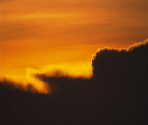 Dark cloud edged in orange light in hazy orange sky Stock Footage 86747712