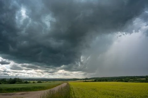 A dark cloud front over the village fields, accompanied by a wave of rain Stock Photos