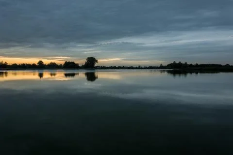 Dark clouds after sunset, over a calm lake Stock Photos