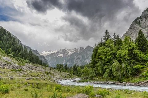 Dark clouds and river down stream view of green valley Stock Photos