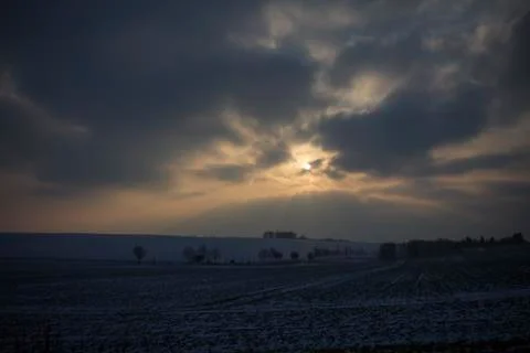 Dark clouds and sun in winter landscape Stock Photos