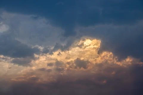 Dark clouds covering sky with dramatic sunset light Stock Photos