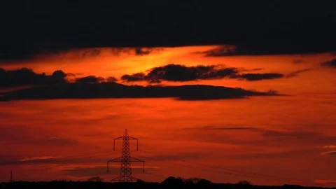 Dark clouds drifting past elctricity pylon during a golden sunset. timelapse Stock Footage 77576077
