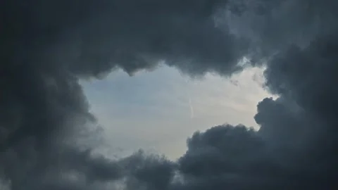 Dark clouds fill the sky as a break forms, showing patches of blue. This Vídeos de archivo 344440603