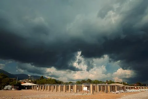 Dark clouds fill sky over  coastal area. Empty structures line beach as weath Foto stock