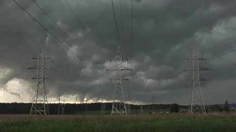 Dark clouds float across sky against electric power pylons of transmission line Stock Footage 92277388