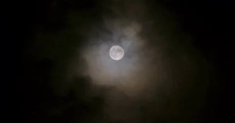 Dark clouds floating by slowly in front of the full moon on a silent night Stock Footage 80592793