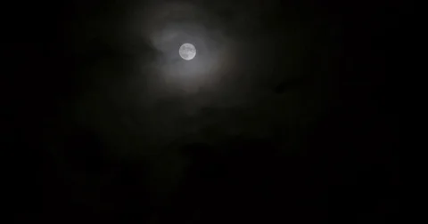 Dark clouds floating by slowly in front of the full moon on a silent night Stock Footage