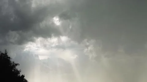 Dark clouds gather as rays of light pierce through the ominous sky 스톡 동영상 307425936