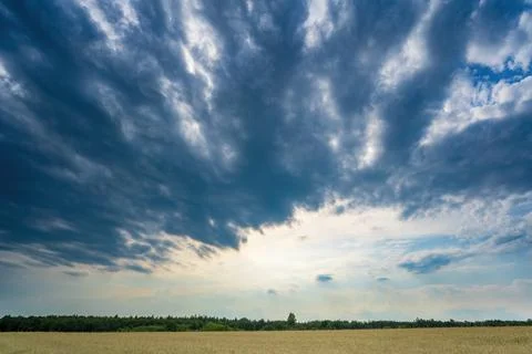 Dark clouds gathering over with sunlight breaking through near the horizon Stock Photos