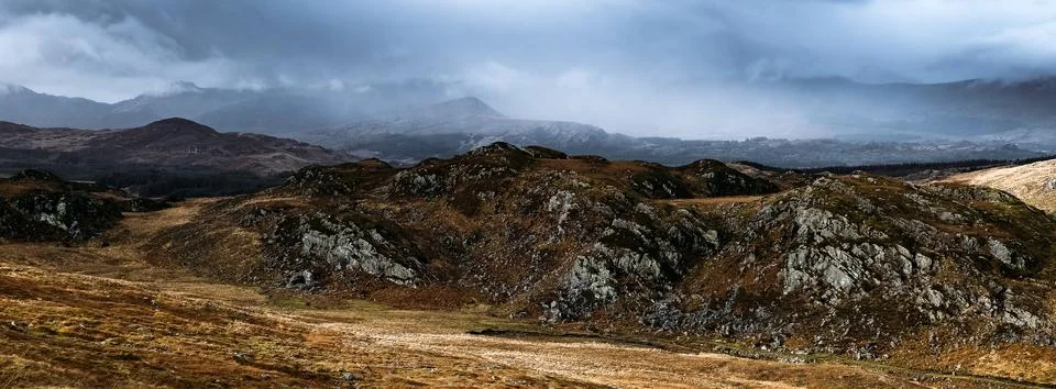 Dark clouds hover over the rugged terrain, creating a dramatic atmosphere. Stock Photos