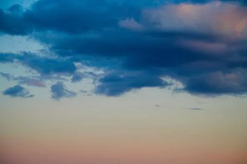 Dark clouds in the light of the setting sun, evening light in the sky, blue c Stock Photos