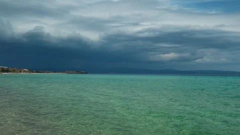 Dark clouds loom low over turquoise sea. Trani Ammouda, Greece Stock Footage 339618977