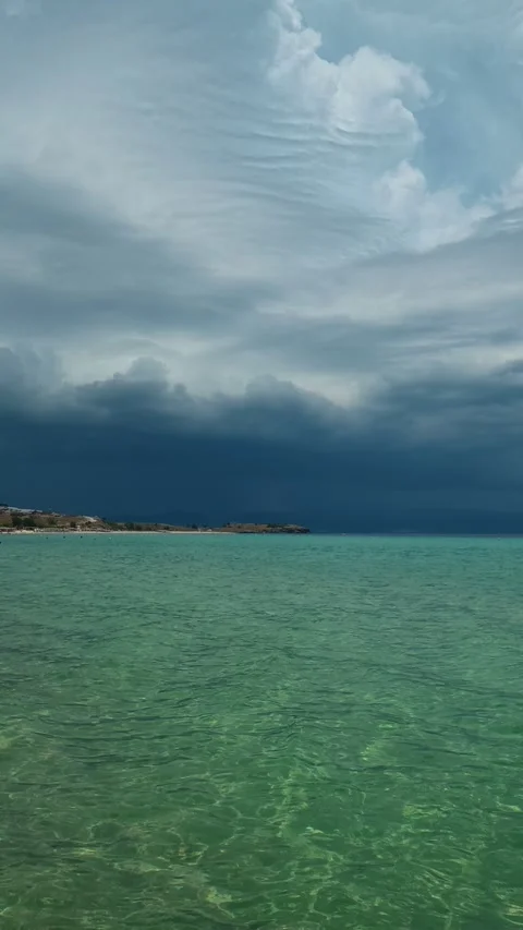 Dark clouds loom low over turquoise waters. Trani Ammouda, Vertical Stock Footage 340651182