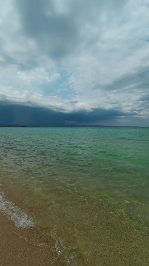 Dark clouds loom over calm, green-tinted sea waters. Trani Ammouda, Vertical Stock Footage 340651168