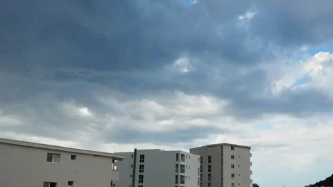 Dark clouds loom over contemporary residential buildings in an urban area. 스톡 동영상 316625271
