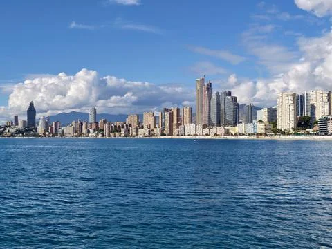 Dark Clouds Loom Over Vibrant Coastal City, Foreboding Sky Casts Shadows On Stock Photos