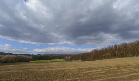 Dark clouds over the field and trees. Sky and field in the spring. Stock Photos