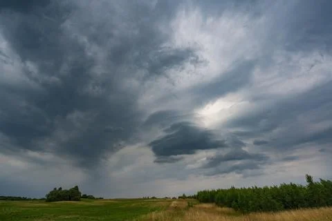 Dark clouds over a lush green landscape and impressive cloud formations Stock Photos