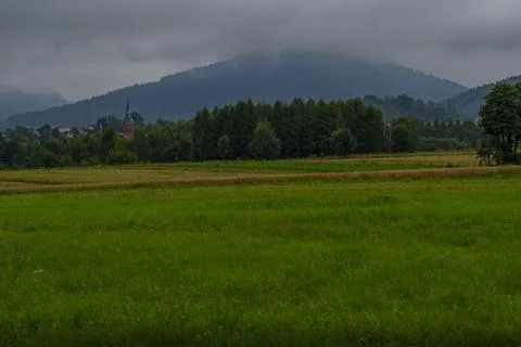 Dark Clouds over Meadow with Distant Church Stock Photos