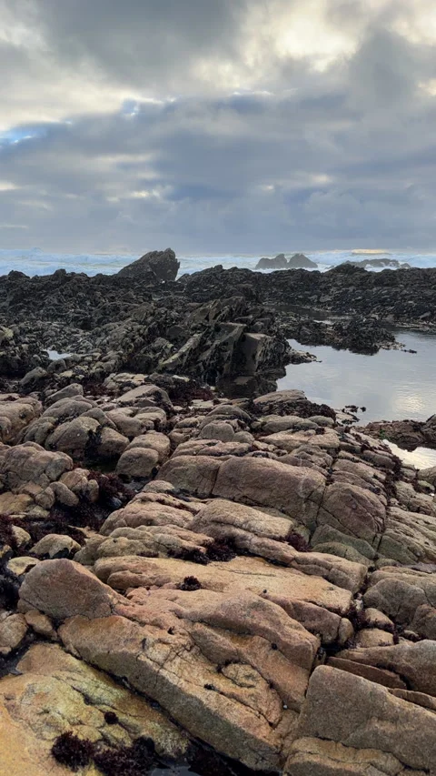Dark clouds over ocean as waves break against rocks in background Stock Footage 237753839