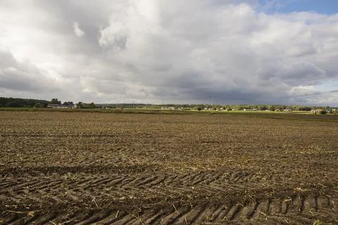 Dark clouds over the plowed field and the village in the background. Autumn. Stock Photos