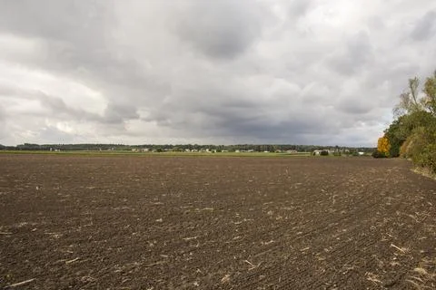 Dark clouds over the plowed field and the village in the background. Autumn. Stock Photos